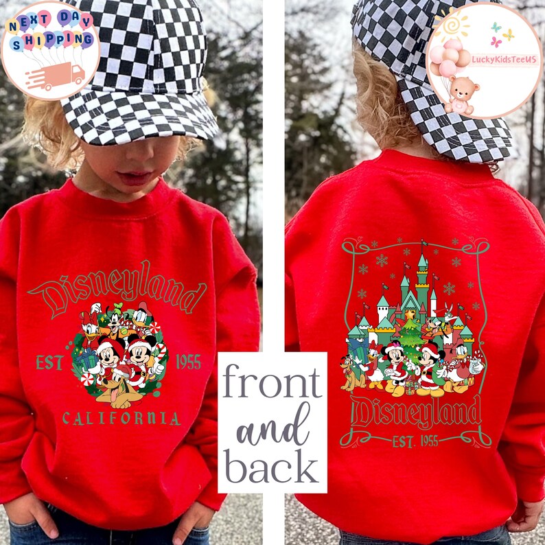 May include: Red sweatshirt with a Christmas-themed Disneyland design on the back. The front of the sweatshirt has a smaller Disneyland logo with the text "EST 1955 CALIFORNIA".