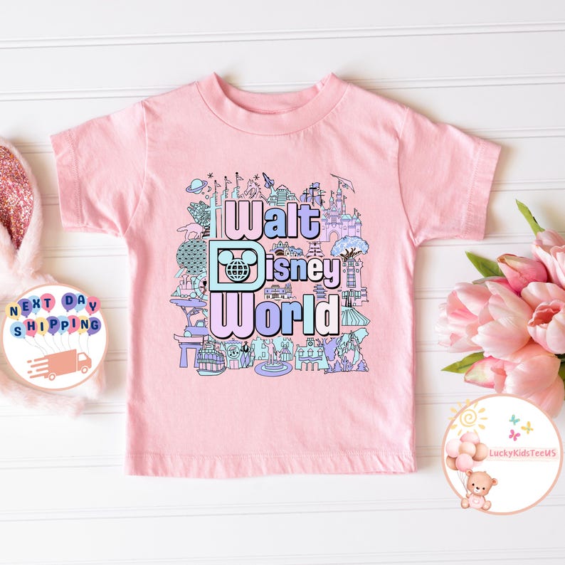 May include: Pink t-shirt with a colorful graphic of Walt Disney World landmarks and the text "Walt Disney World".