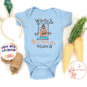 May include: Light blue baby onesie with a cartoon drawing of Mr. Potato Head in a wanted poster. The poster says "Wanted" and "&pound;50 Billion Reward".