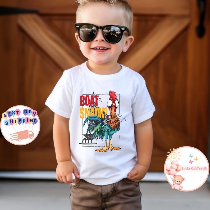 Peut inclure: Un t-shirt blanc avec un dessin de coq de dessin anim&eacute; et le texte "BOAT SNACK ?". Le coq est repr&eacute;sent&eacute; en rouge, orange, bleu et vert. Le t-shirt est port&eacute; par un enfant portant des lunettes de soleil.