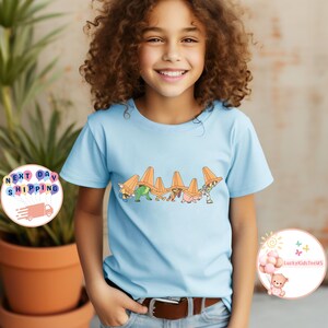 May include: A white ceramic mug with a black handle and the text "But First, Coffee" in a black, handwritten-style font. The mug is on a white surface.