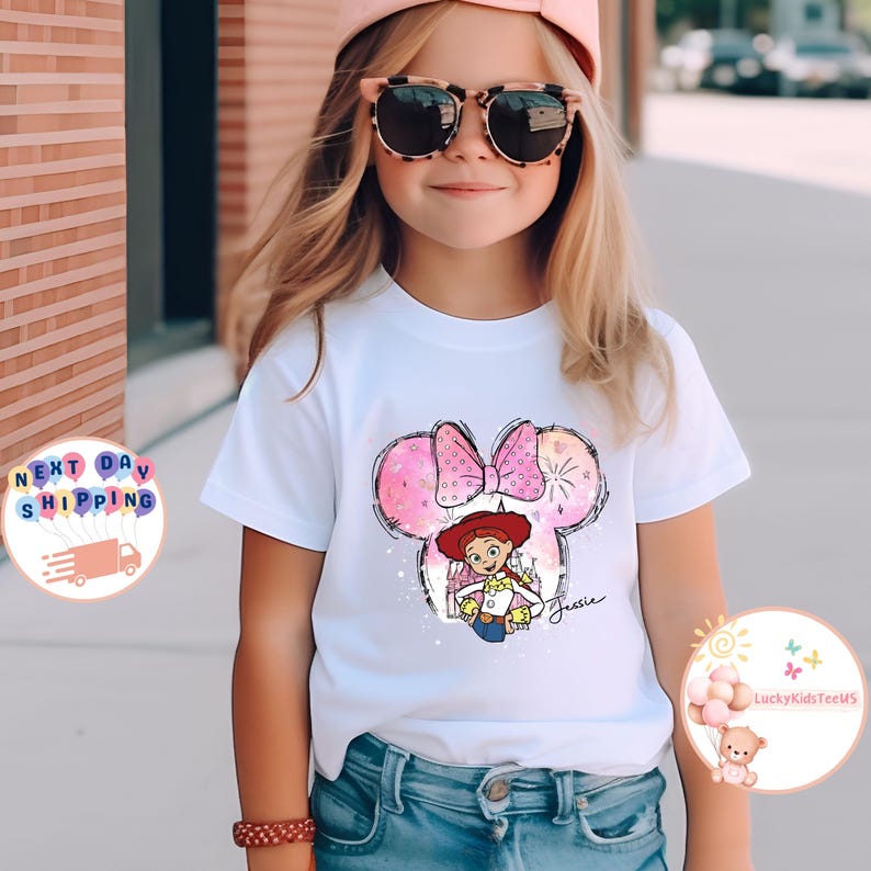 May include: White t-shirt with a pink and white Minnie Mouse ears design featuring a cartoon image of Jessie from Toy Story. The design includes a pink bow and the name "Jessie" written in cursive.