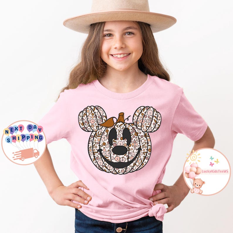 May include: A pink t-shirt with a floral pumpkin Mickey Mouse design. The shirt is made of a soft, comfortable material and is perfect for fall.