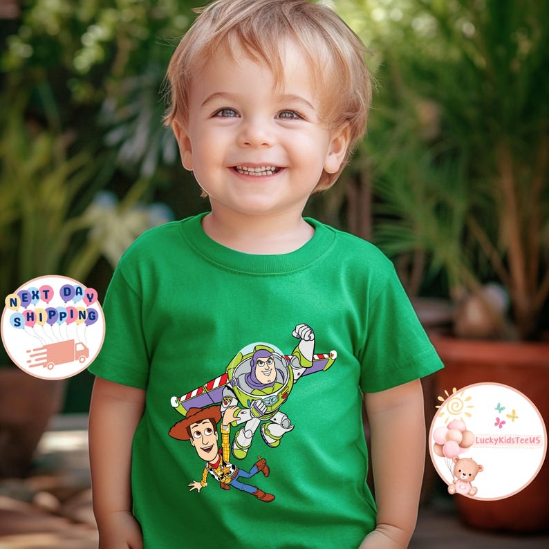 May include: A green t-shirt featuring a graphic of Buzz Lightyear and Woody from Toy Story. The shirt is worn by a young child. The image also includes a logo with the text "LuckyKidsTeeUS".
