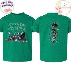 May include: Green t-shirt with a Star Wars Christmas design. The front shows characters wearing Santa hats, with "STAR WARS" text. The back features a vertical arrangement of characters with festive decorations.