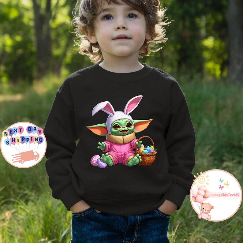 May include: A black sweatshirt with a green, pink, and white cartoon character wearing bunny ears and holding a basket of colorful eggs. The character is holding a basket of colorful eggs. The text "LuckyKidsTeens" is visible in the lower right corner of the image.