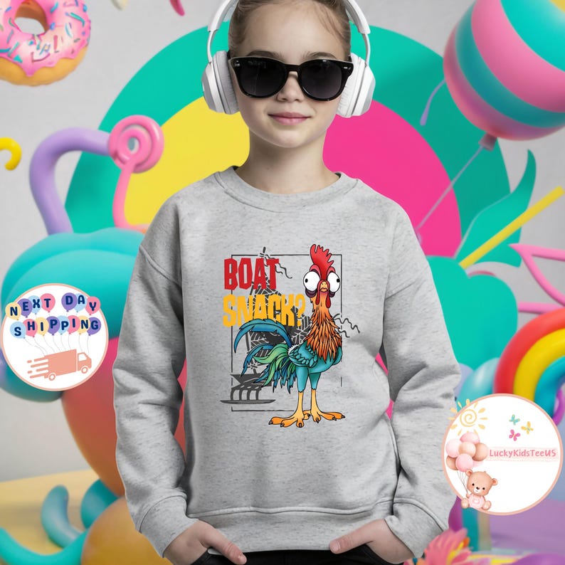 Peut inclure: Un sweat-shirt gris clair avec un motif de coq de dessin anim&eacute; et le texte "BOAT SNACKS?" en rouge et jaune. Le coq a des plumes rouges, orange, bleues et vertes. Le sweat-shirt est de style d&eacute;contract&eacute;.