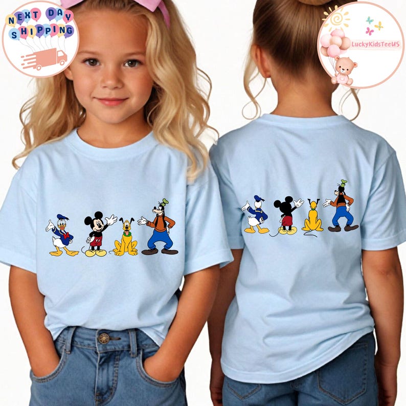 Op de afbeelding: Lichtblauwe T-shirts met cartoonfiguren. De voorkant van de shirts toont Donald Duck, Mickey Mouse, Pluto en Goofy. Dezelfde karakters zijn op de achterkant gedrukt. De shirts worden door kinderen gedragen. De tekst "Next Day Shipping" staat in een cirkel.