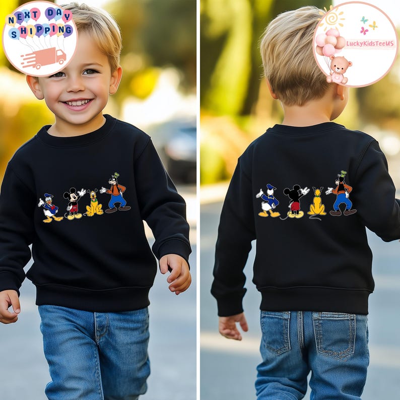 Op de afbeelding: Zwart sweatshirt met een kleurrijk ontwerp van Disney-figuren: Donald Duck, Mickey Mouse, Pluto en Goofy. Het sweatshirt wordt door een kind gedragen. Het ontwerp herhaalt zich op de achterkant.