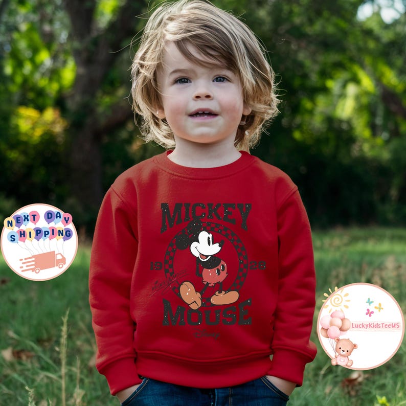 K&ouml;nnte beinhalten: Roter Langarm-Pullover mit einem schwarz-wei&szlig;en Motiv von Mickey Mouse. Das Motiv sagt "Mickey Mouse" und hat ein kariertes Muster.