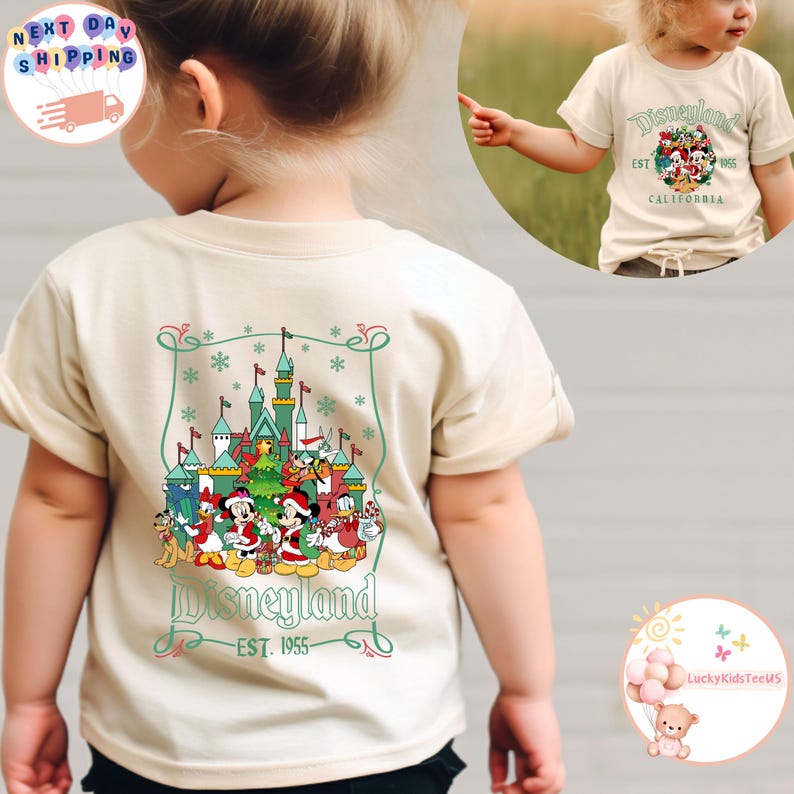 May include: A beige t-shirt with a colorful graphic of the Disneyland castle and characters. The text "Disneyland - EST. 1955" is printed below the graphic.