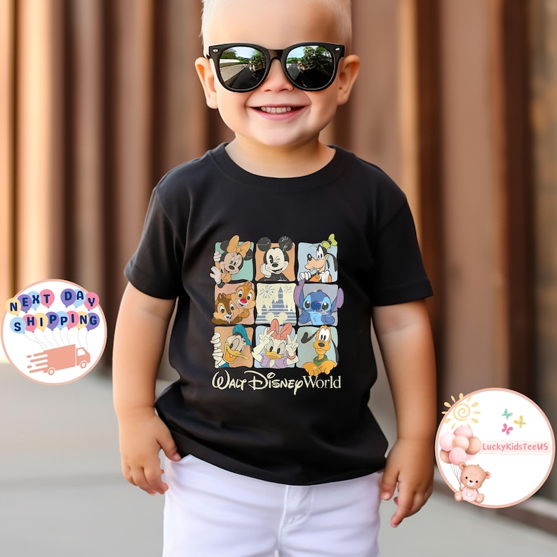 Puede incluir: Camiseta negra con una cuadr&iacute;cula de personajes de Disney, incluyendo Mickey Mouse, Minnie Mouse y el Pato Donald. Las palabras "Walt Disney World" est&aacute;n impresas debajo. La camiseta la lleva un ni&ntilde;o con gafas de sol.