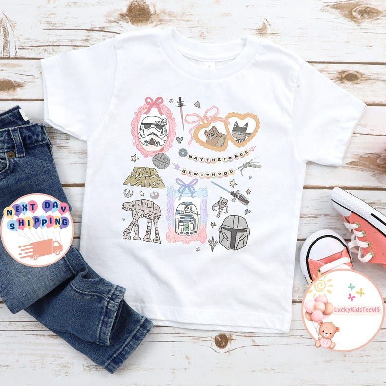 May include: White t-shirt with Star Wars illustrations, including a Stormtrooper and R2-D2, and the phrase "May the Force Be With You." The design is paired with blue jeans and pink trainers.