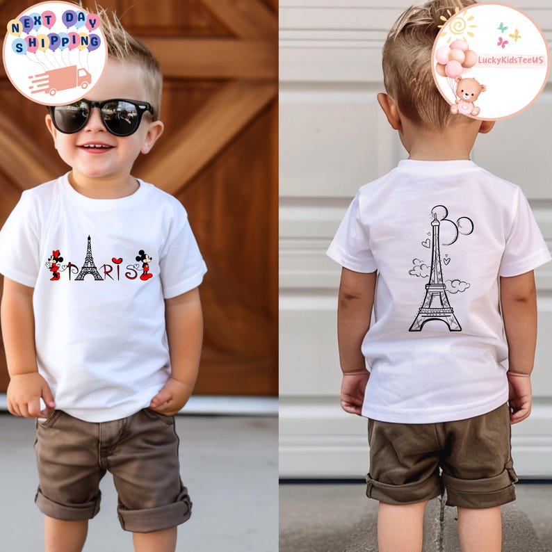 May include: White t-shirt with a black and white Eiffel Tower graphic on the back and a Mickey Mouse and Minnie Mouse graphic with the word "PARIS" on the front. The shirt is being worn by a young child.