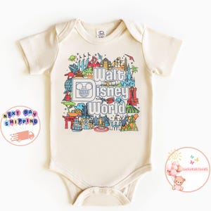 Pu&ograve; includere: Un body beige per neonato con una stampa grafica colorata del logo di Walt Disney World e varie attrazioni. Il testo "Walt Disney World" &egrave; stampato in nero.