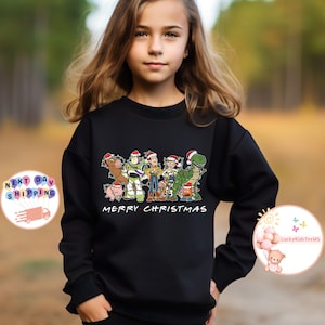 May include: Black sweatshirt with a graphic of the Toy Story characters wearing Santa hats. The text "Merry Christmas" is printed below the graphic.