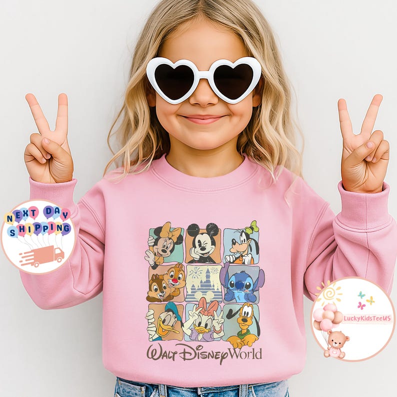 Puede incluir: Sudadera rosa claro con un dise&ntilde;o de personajes de Disney, incluyendo a Mickey y Minnie Mouse. El texto "Walt Disney World" est&aacute; impreso en la parte inferior. La persona de la imagen lleva gafas de sol con forma de coraz&oacute;n.