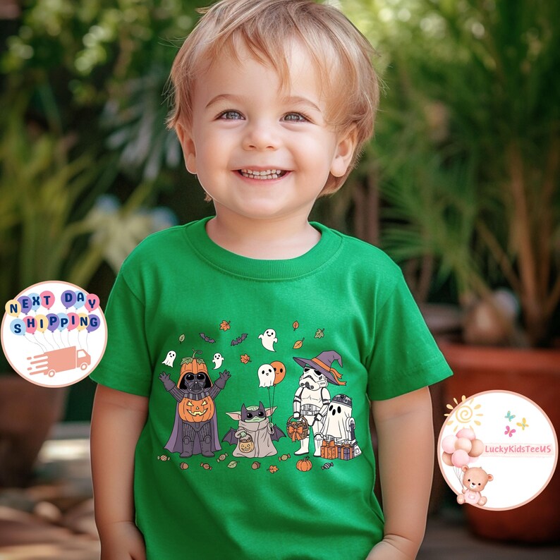 以下が含まれることがあります： ハロウィーンをテーマにした漫画のキャラクター、ダース・ベイダー（カボチャ）、ベビーヨーダ、ストームトルーパーが描かれた緑色のTシャツ。 Tシャツは丸首で半袖です。 画像には「LuckyKidsTeeUS」という文字も含まれています。