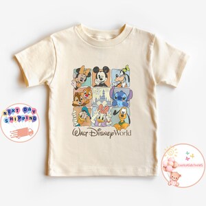 Puede incluir: Camiseta color crema con una cuadr&iacute;cula de personajes de Disney, incluyendo Mickey Mouse, Minnie Mouse, Donald Duck y Stitch. Las palabras "Walt Disney World" est&aacute;n impresas debajo.