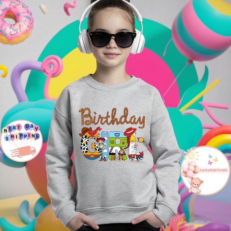 Op de afbeelding: Grijs sweatshirt met een afbeelding van Toy Story-personages die "Birthday Girl" spellen.