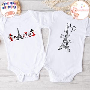 May include: Two white baby onesies with a black and white Eiffel Tower design. One onesie has the text "PARIS" with a red heart and Mickey Mouse characters.
