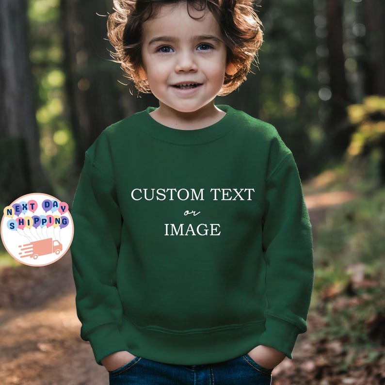 May include: A dark green sweatshirt with the text "CUSTOM TEXT or IMAGE" in white. The sweatshirt is worn by a young child. The image also includes a graphic with the words "NEXT DAY SHIPPING".