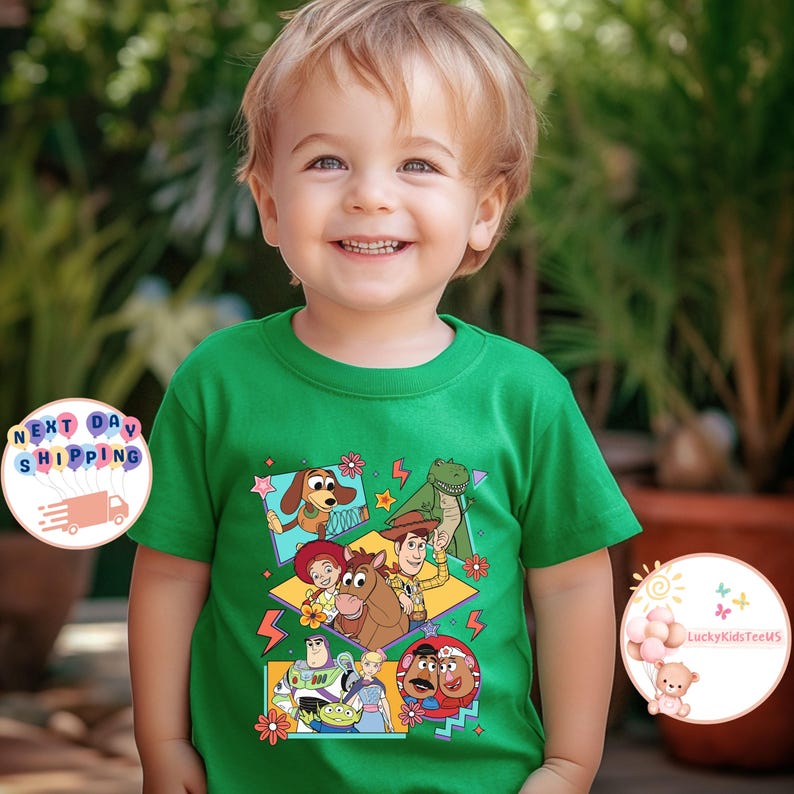 Op de afbeelding: Groen T-shirt met een kleurrijke grafische print van personages uit de Toy Story-filmfranchise. De personages zijn Woody, Buzz Lightyear, Jessie, Rex en Slinky Dog. De grafiek is in retro-stijl met geometrische vormen en bliksemschichten.