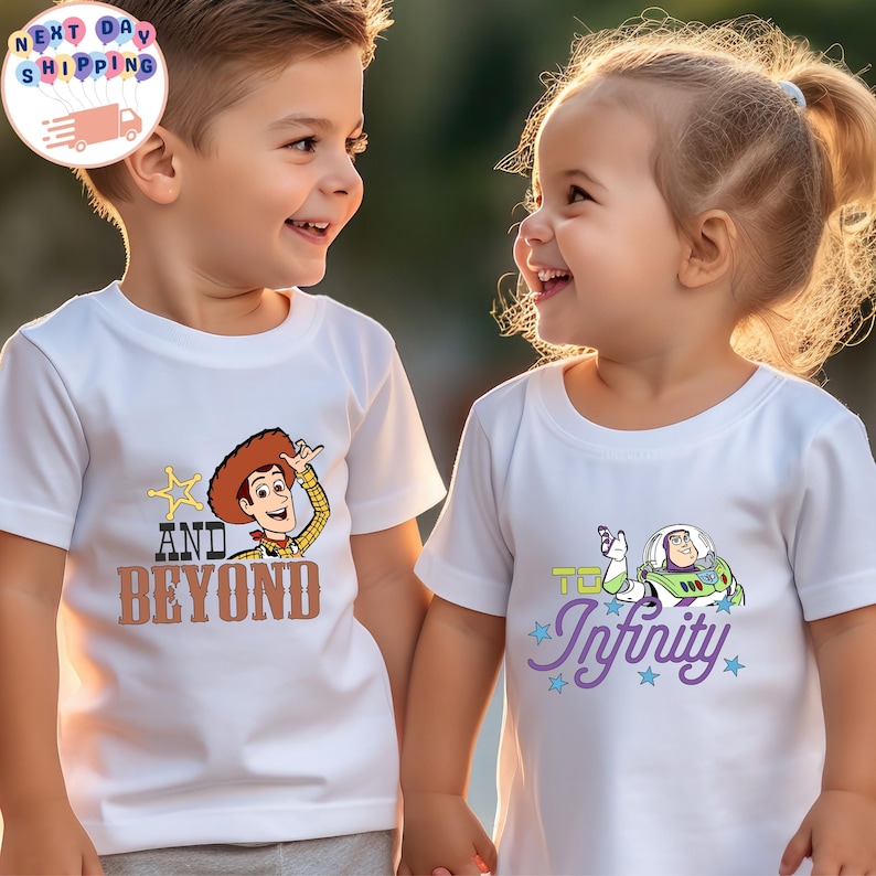 May include: Two children wearing white t-shirts with Toy Story graphics. One shirt features Woody with "AND BEYOND" text, the other has Buzz Lightyear with "TO Infinity" text. Both children are smiling.