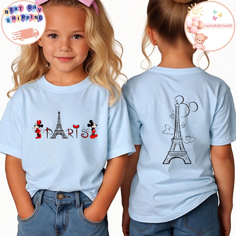 May include: Light blue t-shirt with a graphic of Mickey Mouse and Minnie Mouse in front of the Eiffel Tower with the word "PARIS" underneath. The back of the shirt has a graphic of the Eiffel Tower with Mickey Mouse ears.