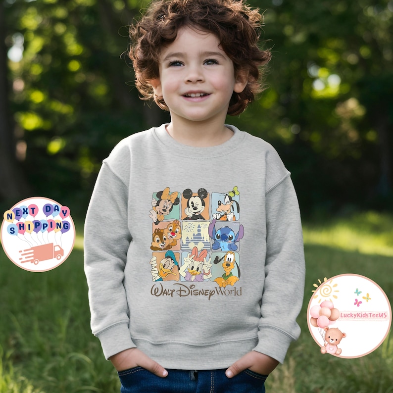 Puede incluir: Una sudadera gris claro con un dise&ntilde;o de cuadr&iacute;cula que muestra personajes de Disney, como Mickey Mouse y el Pato Donald. Las palabras "Walt Disney World" est&aacute;n impresas debajo de la cuadr&iacute;cula. La sudadera la lleva un ni&ntilde;o peque&ntilde;o.