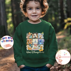 Puede incluir: Sudadera verde oscuro con una cuadr&iacute;cula de ilustraciones de personajes de Disney, como Mickey Mouse y Donald. El texto "Walt Disney World" est&aacute; impreso debajo. La sudadera la lleva un ni&ntilde;o.