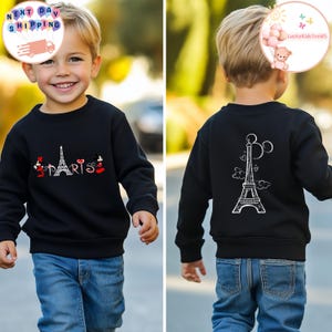 May include: Black sweatshirt with a white Eiffel Tower design on the back and a red "Paris" design with Mickey Mouse characters on the front.