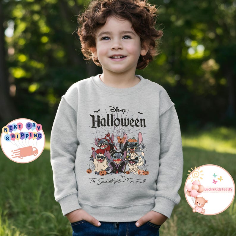 May include: A light gray Disney Halloween sweatshirt featuring a group of cartoon characters in Halloween costumes. The text "Disney Halloween" is above the characters, and "The Spookiest Place On Earth" is below.