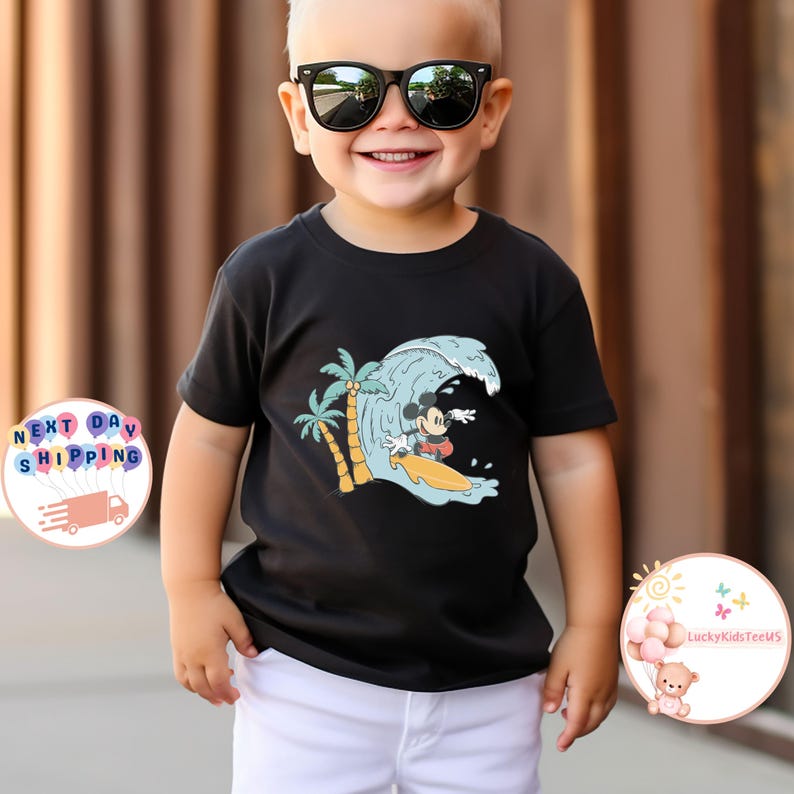 Puede incluir: Camiseta negra con un gr&aacute;fico de Mickey Mouse surfeando en una ola con palmeras en el fondo.