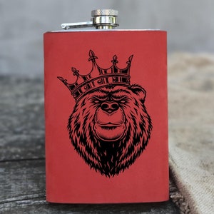 May include: Red stainless steel flask with a black and white illustration of a bear wearing a crown.