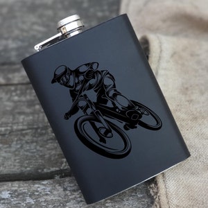 May include: Black metal flask with a silhouette of a person riding a mountain bike.