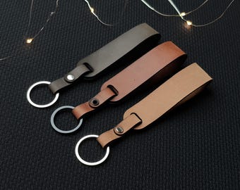 May include: Three leather keychains with silver key rings. The keychains are brown, tan, and light brown.