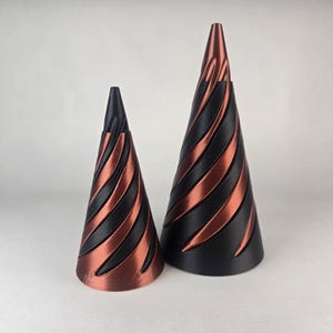 May include: Two black and copper cone-shaped ring holders. The larger cone is about 10 inches tall and the smaller cone is about 5 inches tall.
