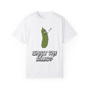 Puede incluir: Camiseta blanca con un pepinillo verde de dibujos animados cantando con el texto "Whats the Dillio?"