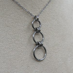 May include: A silver chain necklace with a pendant made of four interlocking metal rings.