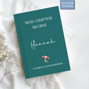 May include: A teal journal with the words "New Chapter Begins" and the name "Hannah" in white script. A small beach umbrella and chair graphic is below the name. The text "Sunshine & New Beginnings" is at the bottom. A small box in the upper right corner says "12 Colour Options."