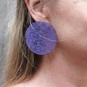 May include: A pair of purple round earrings with a delicate, intricate geometric pattern. The earrings are made of a lightweight material and have a modern, minimalist design.