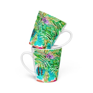 May include: Two white ceramic mugs with a tall, tapered shape. Both mugs feature a colorful, abstract design of palm trees and tropical foliage in shades of green, blue, pink, and yellow.