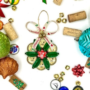 May include: A Christmas ornament made from bottle caps with a green, red, and white color scheme. The ornament features a dog and the text "Merry Christmas".