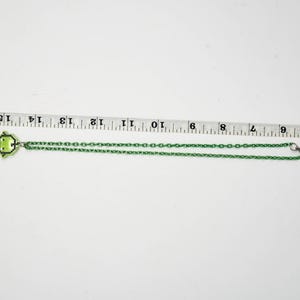 Pu&ograve; includere: Una collana verde con un ciondolo a forma di rana. La catena &egrave; verde e ha una chiusura a moschettone. Il ciondolo &egrave; un design a rana pixelato. La collana misura circa 40 cm di lunghezza.