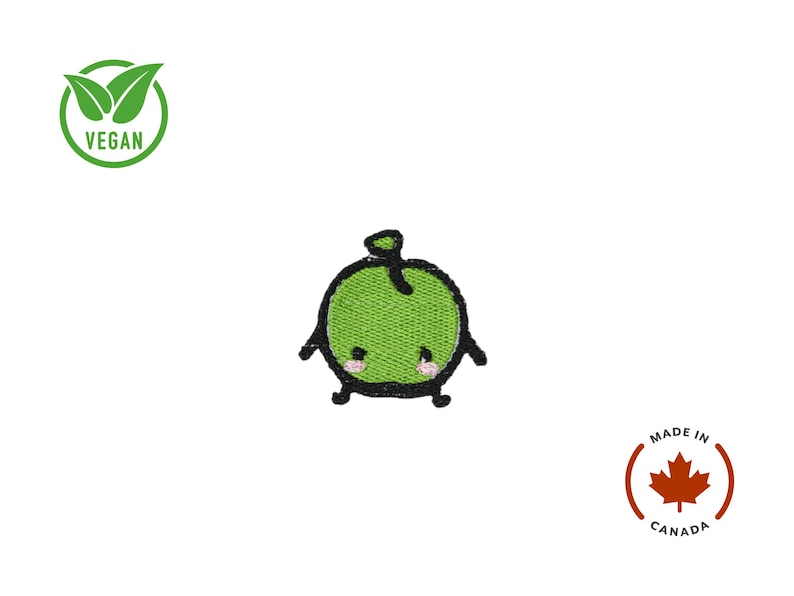 Puede incluir: Parche bordado de manzana verde con una cara sonriente, contornos negros y brazos y piernas peque&ntilde;os. El parche tiene un s&iacute;mbolo vegano y un emblema "Made in Canada".