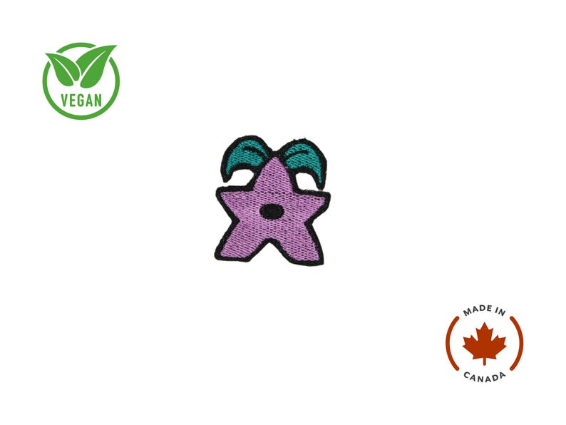 K&ouml;nnte beinhalten: Gestickter Aufn&auml;her mit einem lila Stern mit t&uuml;rkisfarbenen Akzenten und schwarzer Umrandung. Der Aufn&auml;her hat einen kleinen schwarzen Kreis in der Mitte. Das Bild enth&auml;lt auch ein "VEGAN"-Logo und ein "MADE IN CANADA"-Logo.