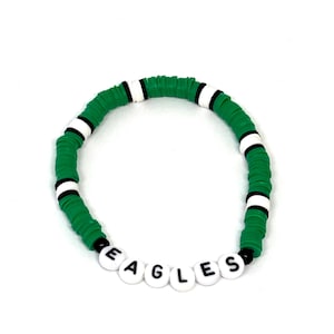 Puede incluir: Pulsera de cuentas verdes y blancas con la palabra "EAGLES" escrita en letras negras sobre cuentas blancas.