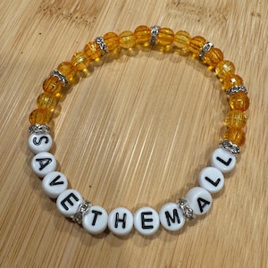 Puede incluir: Un brazalete de cuentas amarillas y naranjas con cuentas de letras blancas que deletrean "SAVE THE MALL".