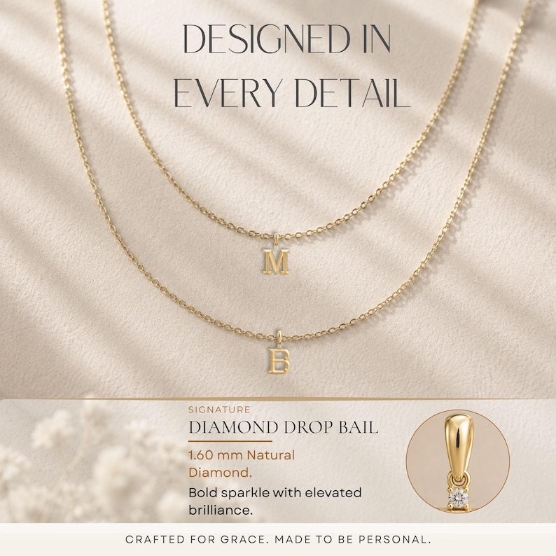 May include: Two delicate gold necklaces with letter pendants, one with an "M" and the other with a "B". The image includes text that reads "DESIGNED IN EVERY DETAIL" and "DIAMOND DROP BAIL". A small diamond is featured.